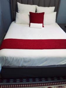 Bett mit roter und weißer Bettwäsche und Kissen in der Unterkunft PS GOOD TIME GUEST HOUSE in Klerksdorp