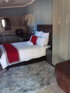 ein Schlafzimmer mit einem großen Bett mit weißen und roten Kissen in der Unterkunft PS GOOD TIME GUEST HOUSE in Klerksdorp