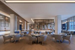 ein Restaurant mit Tischen und Stühlen und eine Küche in der Unterkunft Foshan Marriott Hotel in Foshan