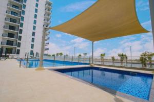 a swimming pool with a large umbrella next to a building at Best deal in town Yas Island 232WB10 in Abu Dhabi