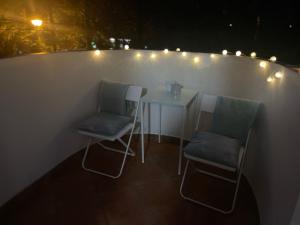 2 sillas y una mesa en un balcón con luces en Pokoje do wynajęcia - Podwisłocze 8a, en Rzeszów