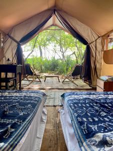 namiot z dwoma łóżkami i stołem w obiekcie Camp Tarimbang w mieście Tandulujangga