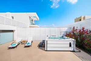a patio with a hot tub and two chairs at Villa Odysseas in Ialysos