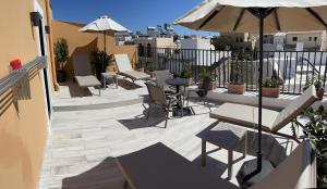 un patio con mesas, sillas y una sombrilla en Antica Canea Luxury Rooms, en La Canea