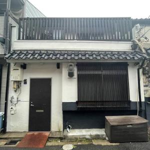 大阪的住宿－茶隐の宿，白色的房子,设有黑色的门和阳台