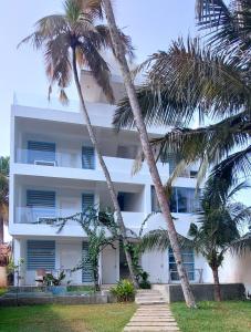 a white building with two palm trees in front of it at NAVA b&b in Mirissa