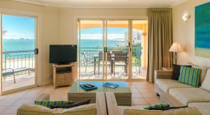 un soggiorno con divano, TV e balcone di Toscana Village Resort ad Airlie Beach
