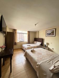 een hotelkamer met 2 bedden en een bureau bij Antara Hostal in Cajamarca