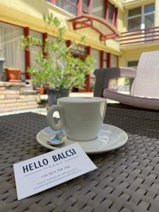 a coffee cup on a table with a sign on it at Hello Balcsi Apartmanház in Tihany