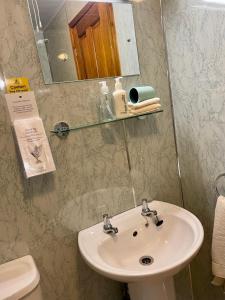 uma casa de banho com um lavatório, um espelho e um WC. em Sunset House B&B em Penrith