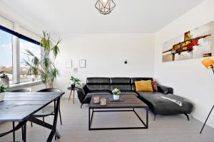 a living room with a black leather couch and a table at Privat, skandinavisk og moderne lejlighed - med gratis parkering in Randers