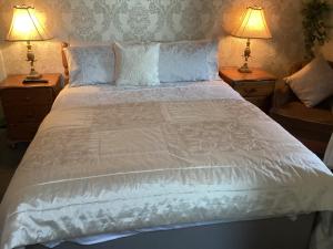 a large white bed with two lamps on two tables at The Old School House B&B in Ballinskelligs