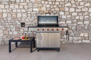 a gas stove with a table in front of a stone wall at Villa Myrto in Ialyssos