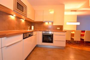 een keuken met witte kasten en een fornuis met oven bij Select Top 11 - by Alpen Apartments in Piesendorf