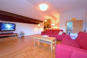 een woonkamer met roze banken en een tv bij Select Top 11 - by Alpen Apartments in Piesendorf