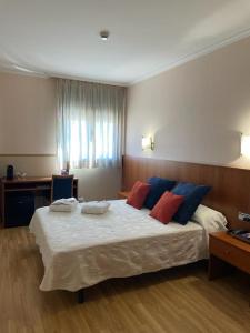 1 dormitorio con 1 cama grande con almohadas azules y rojas en Andamur San Román en San Román