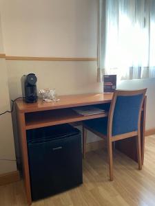 a wooden desk with a blue chair next to a window at Andamur San Román in San Román