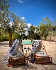 duas cadeiras e uma mesa na areia perto de uma piscina em Felix - Maison d'hôtes em Néffiès