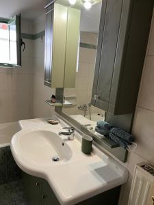 W łazience znajduje się biała umywalka i lustro. w obiekcie Athens Riviera modern apartment w Pireusie
