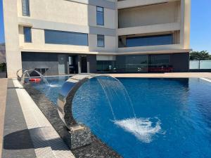 a swimming pool with a fountain in front of a building at Rakabi The Fern, Igatpuri in Igatpuri