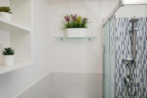 ein Bad mit einer Dusche mit Pflanzen an der Wand in der Unterkunft Monolocale Glicine in Schisò