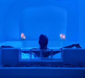 une personne assise dans une baignoire avec une lumière bleue dans l'établissement Loveroom La Cesarine Jacuzzi privé, à Mougins