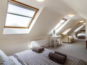 a attic bedroom with a bed and two windows at Rivendell Lodge in East Winch