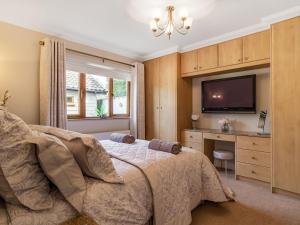 a bedroom with a bed with a television and a desk at Rivendell Lodge in East Winch