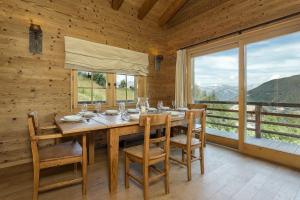 a dining room with a table and chairs and a large window at Chalet Jessica in La Tzoumaz