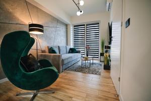 een woonkamer met een groene stoel en een bank bij ApartHome 25 by Housine in Zator