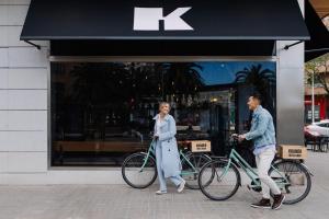 Ein Mann und eine Frau, die ihre Fahrräder vor einem Laden laufen in der Unterkunft Hotel Kramer in Valencia