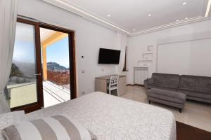 - une chambre avec un lit, un canapé et une télévision dans l'établissement Relais Milò, à Agerola