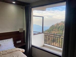 una camera da letto con una grande finestra con vista sulle montagne di The Bliss Dhanaulti a Dhanaulti