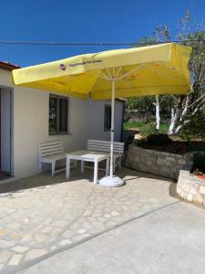 a yellow umbrella on a patio with a table and benches at Villas Ermali in Ksamil