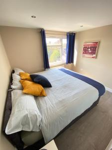 sypialnia z łóżkiem z poduszkami i oknem w obiekcie STUNNING 1 BEDROOM FLAT IN WOOD GREEN w Londynie