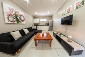sala de estar con sofá negro y mesa en Faraway Lodge, en Durban