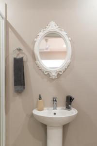 een badkamer met een witte wastafel en een spiegel bij Faraway Lodge in Durban
