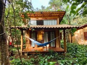 a hammock in front of a house in the forest at Chalés Vila Floresta in Alto Paraíso de Goiás
