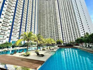 a swimming pool with palm trees and a large building at Jazz Residences Makati City by darpm in Manila
