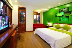 a green bedroom with a bed and a flat screen tv at Thanh Van 1 Hotel in Hoi An