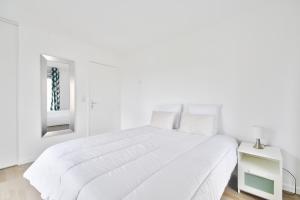 um quarto branco com uma grande cama branca e um espelho em Ecapade en duo a Pleneuf-Val-Andre em Pléneuf-Val-André