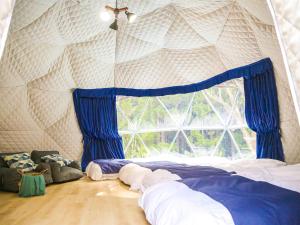 a bedroom with a large window with blue curtains at Lupo Forest "GRAN FOREST Echizen Miyama" - Vacation STAY 07085v in Fukui