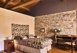 una camera da letto con un muro in pietra, un letto e una scrivania di Bargiolina a Barge