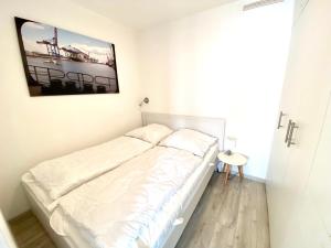 - un lit blanc dans une chambre avec une photo sur le mur dans l'établissement Achtern Diek, Whg 9, à Grömitz