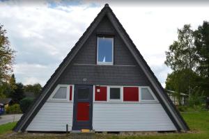 una casa con techo de gambrel con puerta roja en Ferienhaus in Waldkatzenbach modern & renoviert, en Waldbrunn