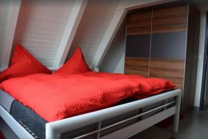 1 dormitorio con cama roja y almohadas rojas en Ferienhaus in Waldkatzenbach modern & renoviert, en Waldbrunn