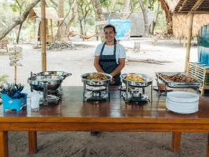 un hombre parado frente a una mesa de madera con comida en Isla - The Island Experience en El Nido