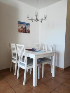 mesa de comedor blanca con 4 sillas blancas en Ferienwohnung-111-im-Berliner-Hof, en Scharbeutz