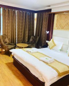 Un dormitorio con una cama grande y una silla. en SIT Hotel Ladakh Horizon Leh, en Leh