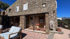 een stenen huis met een veranda en een patio bij Casa di Babbo in Macinaggio